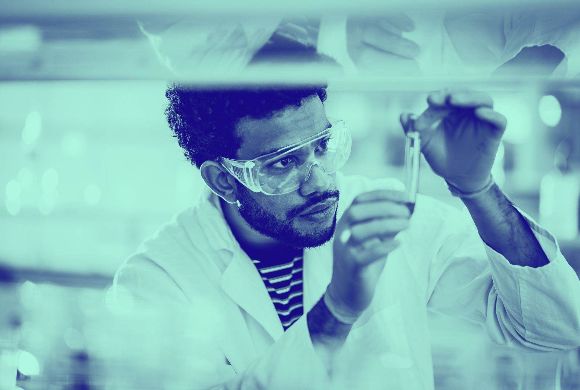 Blue washed image of male in lab looking into test tube