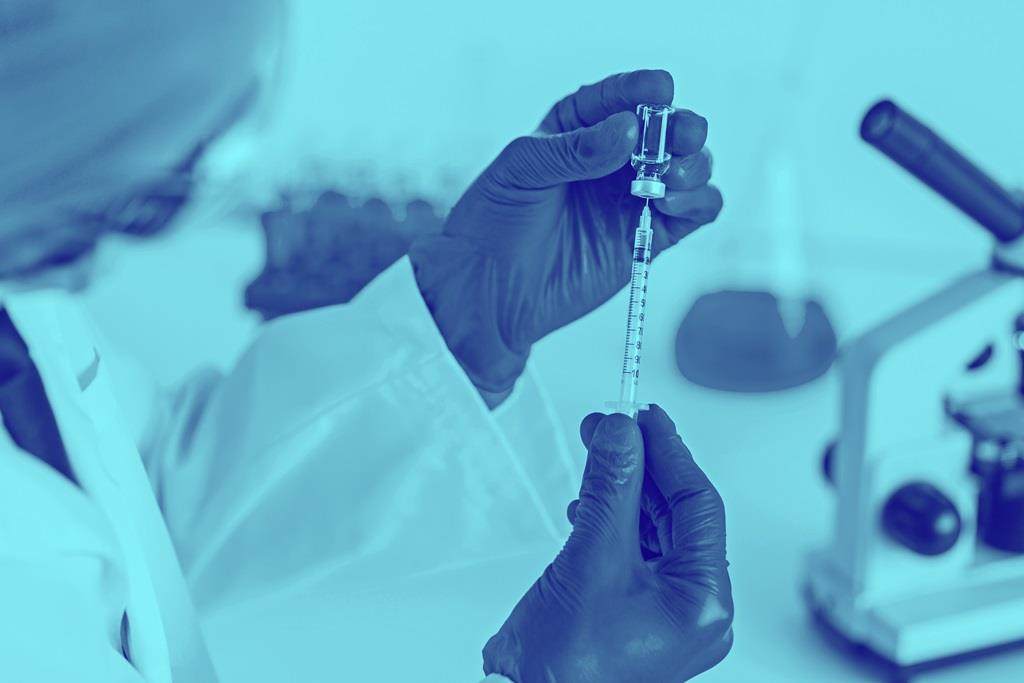 Blue washed image of vaccine being drawn from bottle