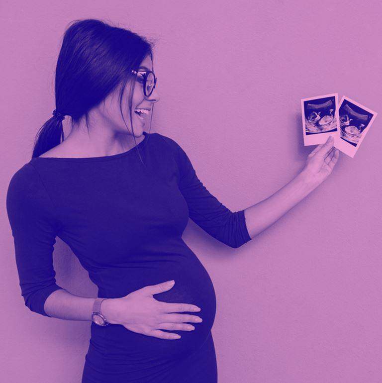 pregnant woman holding out scan photos