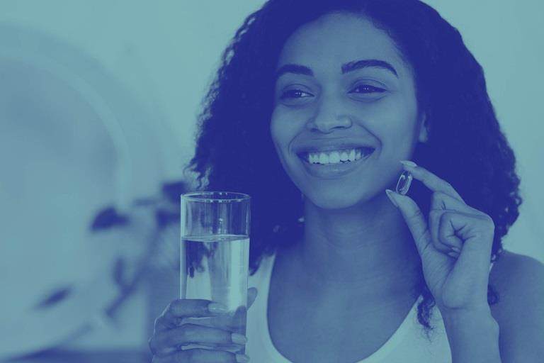 Blue washed image of woman with glass of water about to take a capsule